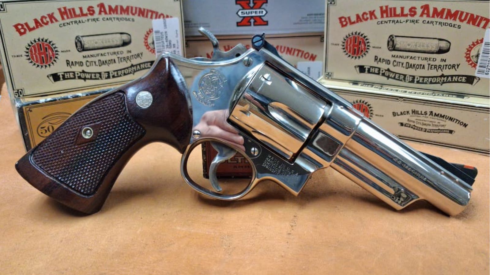 A nickel Smith & Wesson revolver on the counter, with boxes of Black Hills ammunition behind it