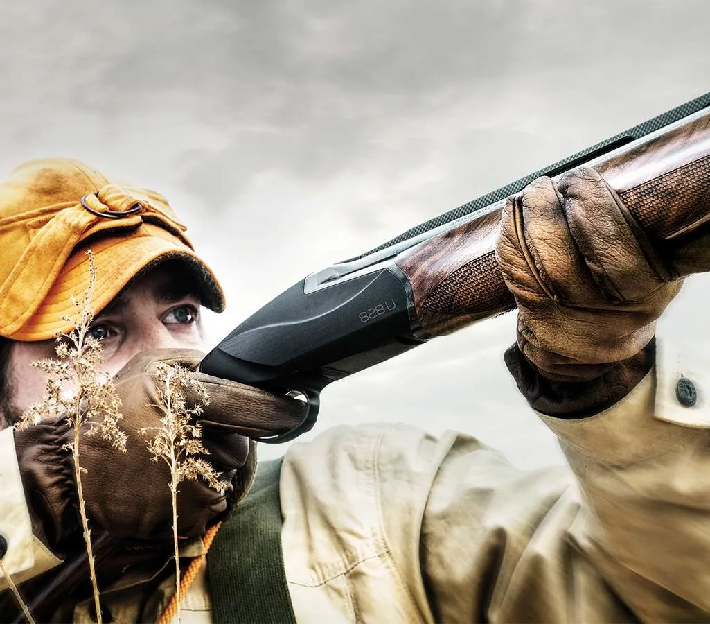 Shooter mounting a walnut-stocked Benelli 828U over-under shotgun