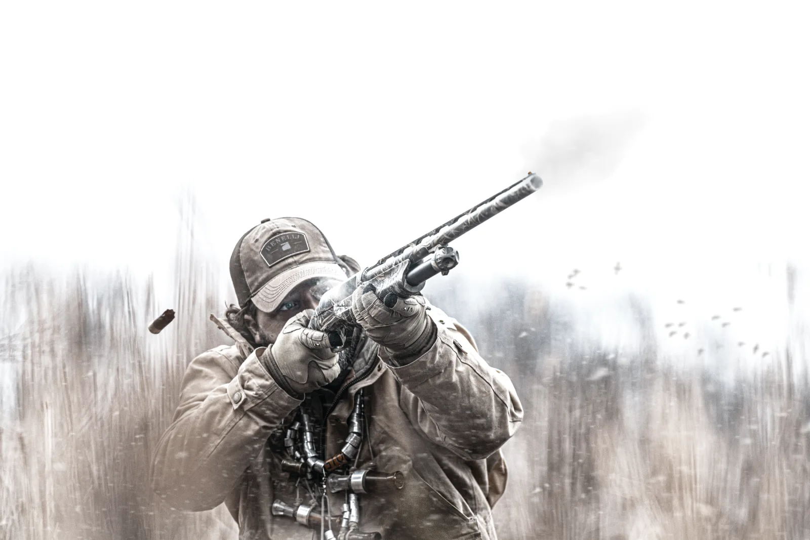 Waterfowl hunter firing a Benelli pump shotgun in snow flurries